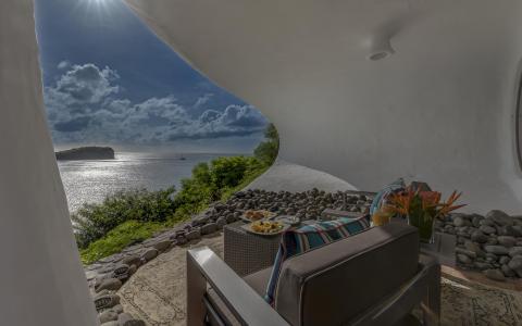 Stylish outdoor lounge with sea view, tropical decor, and modern seating.