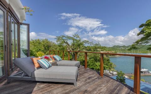 Scenic deck overlooking bay with boats, lush hills, and modern lounge area