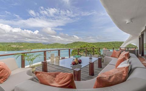 Scenic outdoor terrace with modern furniture overlooking a bay with sailboats