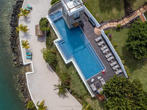 Luxurious coastal property with a large pool, wooden deck, and beach access.
