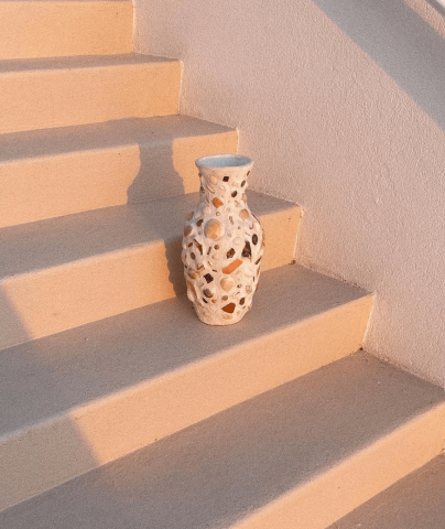 The image shows a decorative vase with a holey or lattice-like design placed on a staircase