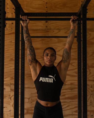 The image shows a woman hanging from a pull-up bar