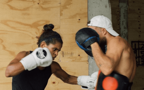 The image shows two people engaged in a boxing training session