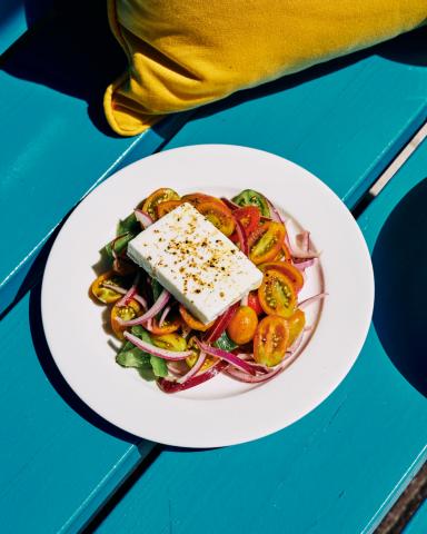 The image depicts a beautifully arranged fresh salad that includes a variety of colorful tomato slices, possibly of heirloom varieties given their varying colors and sizes