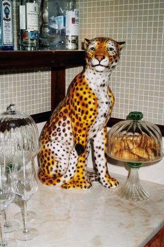 This image shows a vibrant setup that includes a life-sized ceramic or porcelain statue of a leopard prominently placed in the foreground