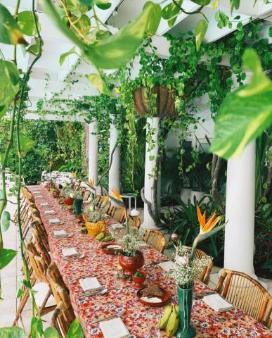 This image features an inviting outdoor dining setting, elegantly decorated with a lush, green ambiance