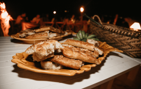 The image shows a selection of freshly baked bread placed on ceramic dishes on a white table