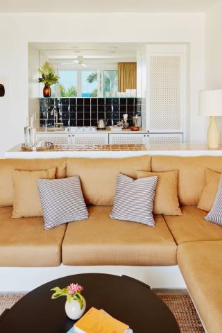 This image shows a stylishly decorated interior space featuring a large beige L-shaped sofa adorned with black and white striped pillows