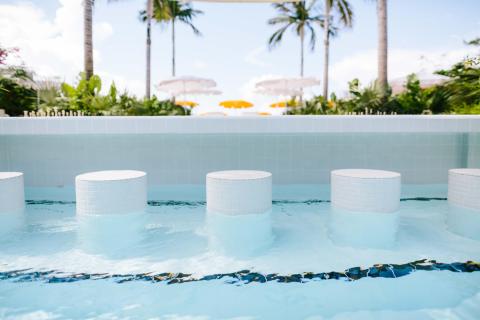 The image features a luxurious outdoor pool setting