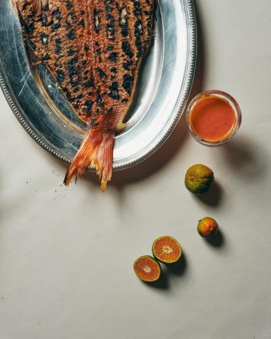 This image features a grilled fish served on a silver platter