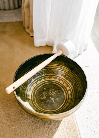 This image features a Tibetan singing bowl with a mallet resting on its rim