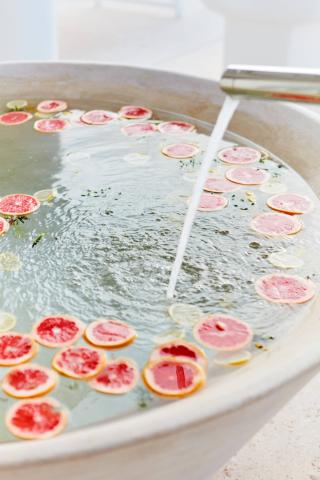 The image shows a large basin or tub filled with water, with slices of fresh citrus fruit (grapefruit and lemon) floating on the surface