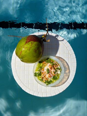 The image shows a food presentation that includes a dish made with ingredients served inside half a coconut