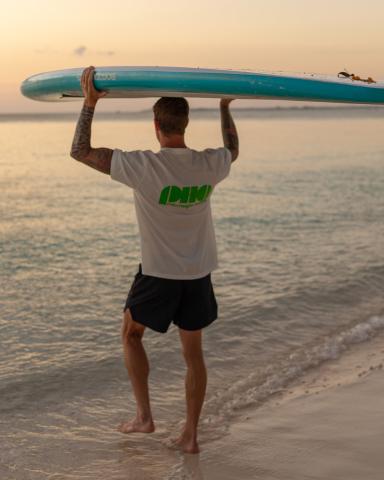 The image shows a man holding a blue surfboard over his head
