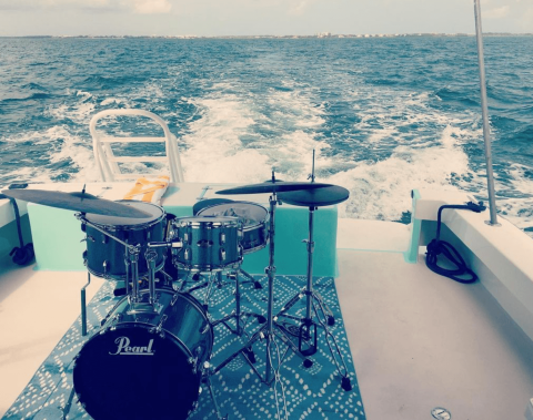 This image shows a drum set on the back of a moving boat