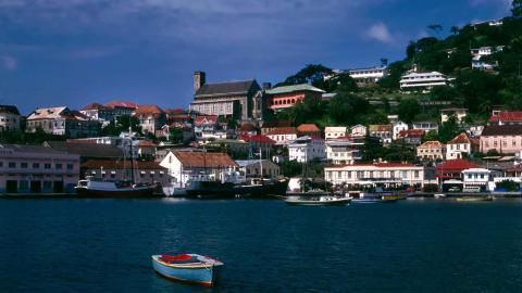 Colorful coastal town with boats in harbor, red-roof buildings, and a towering landmark