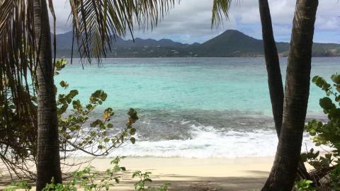 Tropical beach view with turquoise sea, sandy shores, and misty mountains