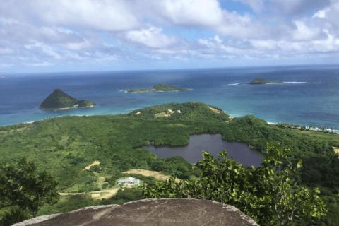 Scenic coastal view of lush islands with lakes, beaches, and buildings under cloudy skies.
