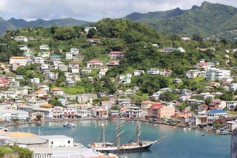 Colorful coastal town with a busy harbor and lush hills, possibly in the Caribbean.