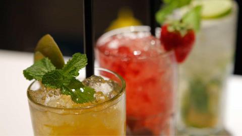 Colorful cocktails with fruits, amber, red, and pale green drinks in glasses