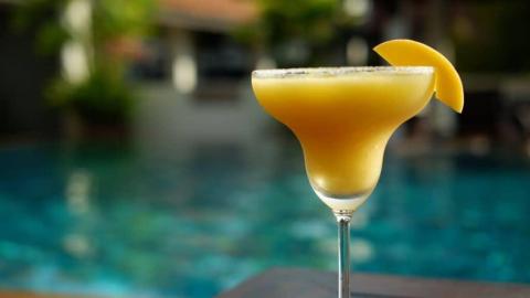 Mango margarita by pool, slice on rim, relaxing resort vibe, chilled.