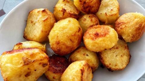 Golden brown roasted potatoes in a white bowl, crispy and fluffy.