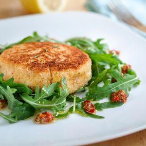 Crisp breaded patty on arugula with sun-dried tomatoes, simple savory dish