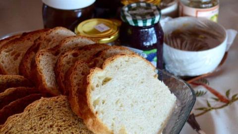 Variety of bread slices with condiment jars and a bowl of spread on a table.
