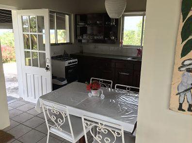Cozy kitchen with dark cabinets and dining area, leading to a green outdoor space.