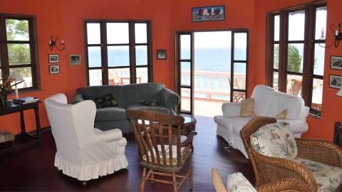 Cozy living room with orange walls and sea view, diverse furniture.