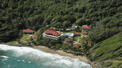 Aerial view of luxury coastal resort with red-roofed buildings and pool