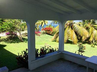 Covered patio view with lush garden, palm trees, and vibrant flowers in a tropical setting