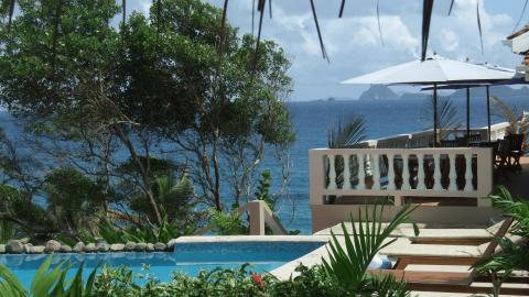 Luxurious seaside resort with pool, lounge chairs, umbrellas, and ocean view