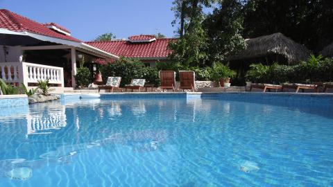 Outdoor swimming pool with sun loungers and a gazebo in a tropical resort setting