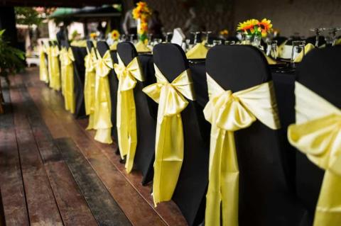Black and yellow themed event setup with decorated chairs and floral table arrangements
