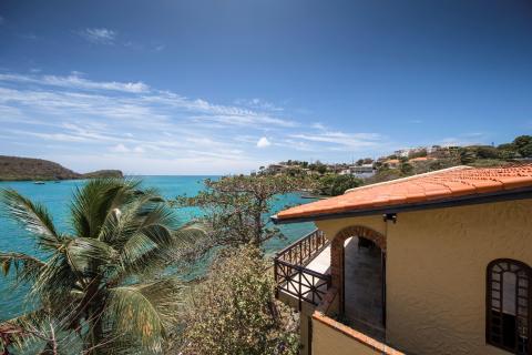Coastal view from yellow stucco building with seascape, boats, and lush foliage