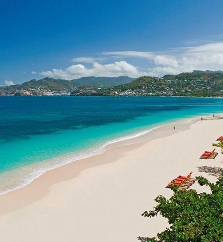 Tropical beach with orange sun loungers, white sand, and clear turquoise waters