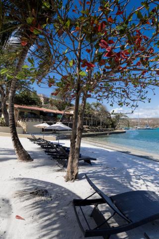 Scenic beach with sun loungers, umbrellas, and a resort under a blue sky
