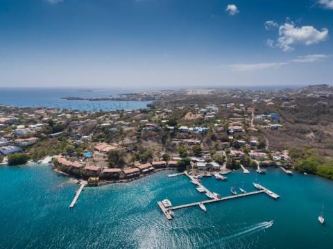 Aerial view of coastal marina with boats, nearby urban and natural landscapes