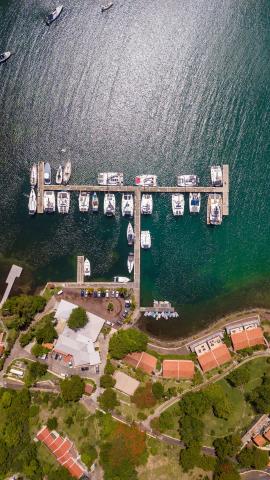 Aerial view of a busy marina with boats docked along piers on a sunny day.