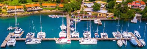 Aerial view of a marina with sailboats, yachts, and coastal resort buildings