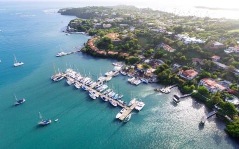 Aerial view of a marina with yachts, surrounded by luxury homes and clear blue waters.