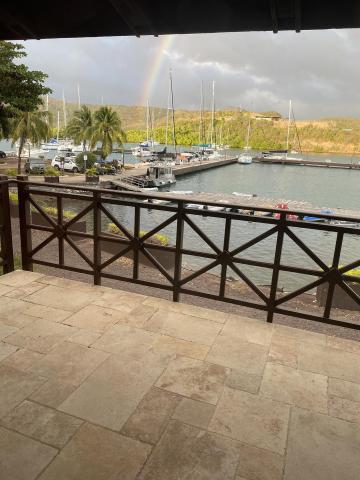 Scenic marina view with boats, rainbow, and hills, ideal for serene outdoor themes.