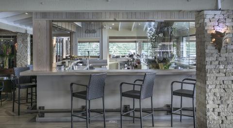 Modern bar with black wicker stools, wood tones, and green outdoor view
