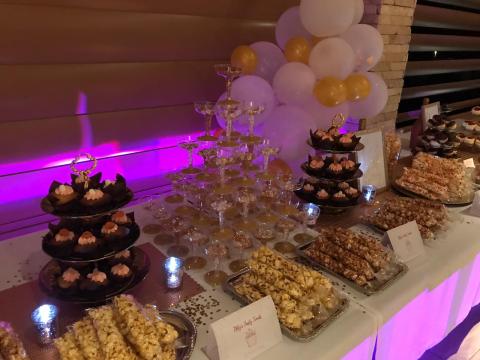 Dessert table with cupcakes, champagne glasses, and treats at festive event.