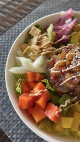 Colorful poke bowl with sashimi-grade tuna, diced vegetables, and fried wonton crisps.