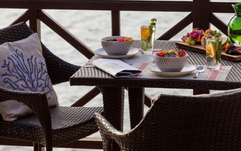 Outdoor dining by water with wicker chairs, fresh meals, and drinks