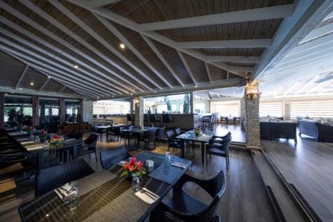 Chic restaurant interior with black chairs, dark tables, and white ceiling beams.