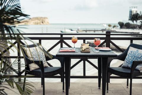 Outdoor seaside dining setup with cocktails and nachos on table