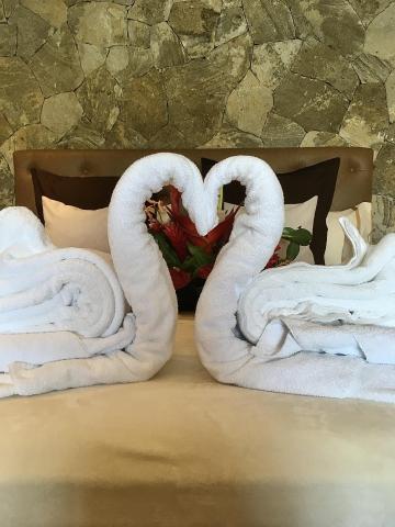 Romantic hotel bed decor with towel swans forming a heart on white bedding
